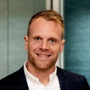 Mandskab i professionelt tøj smiler foran moderne kontormiljø.