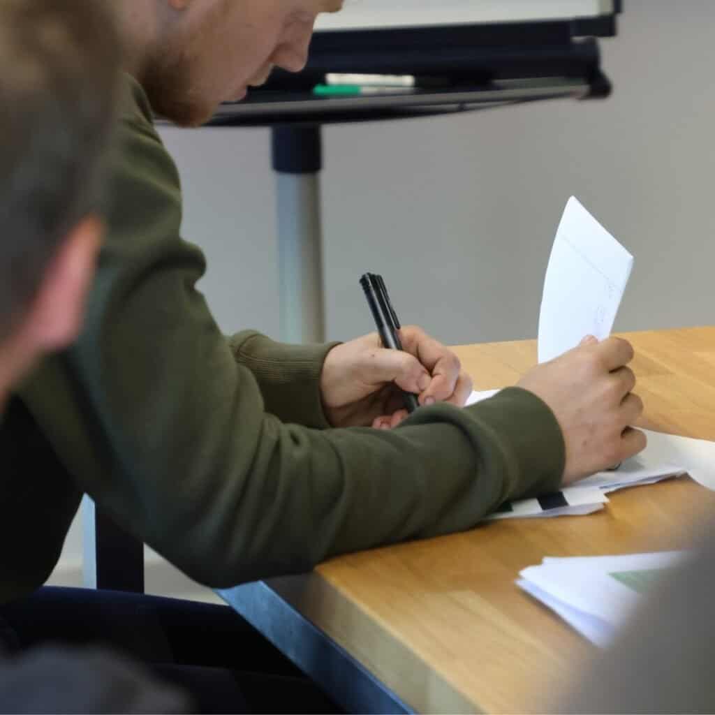 1. Menneske der skriver på papirer ved et mødebamotoer, fokus på arbejds- og forretningsmøder.