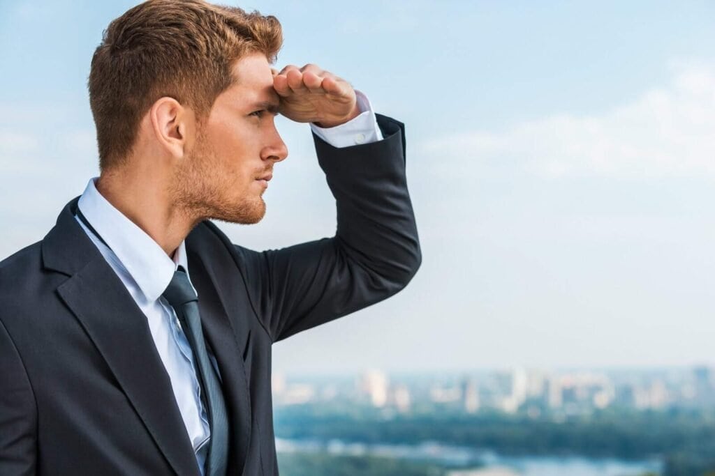 Højtalende forretningsmand ser ud over byen, søger efter muligheder, professionel, erhvervsmand, urban, udendørs, rapport, visionært, lederskab, karriere, fokus, målrettet, succeshøjde.