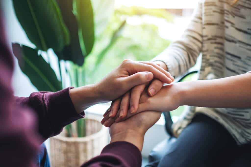 To personer holder hinanden i hånden, symboliserer indre bæredygtighed og trivsel.