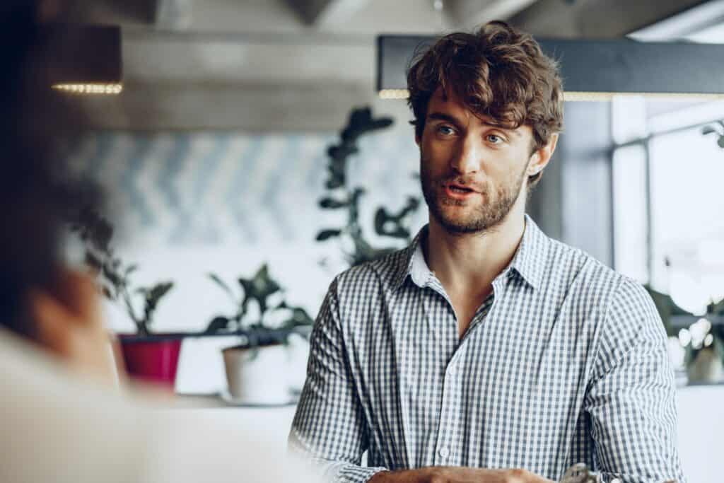 Mand i samtale under medarbejdersamtale hos Humano, fokus på HR og medarbejderudvikling.