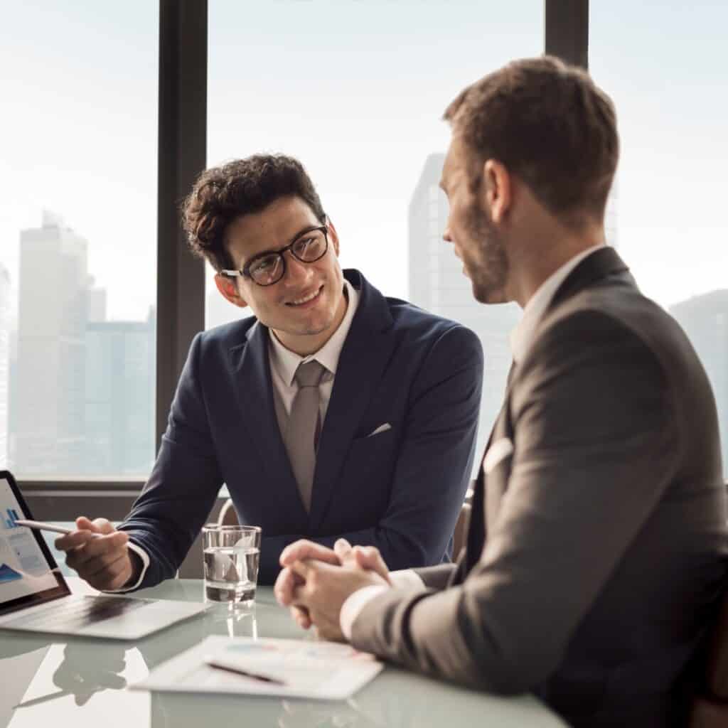 To mænd i forretningsmøde under medarbejdersamtale i moderne kontor.