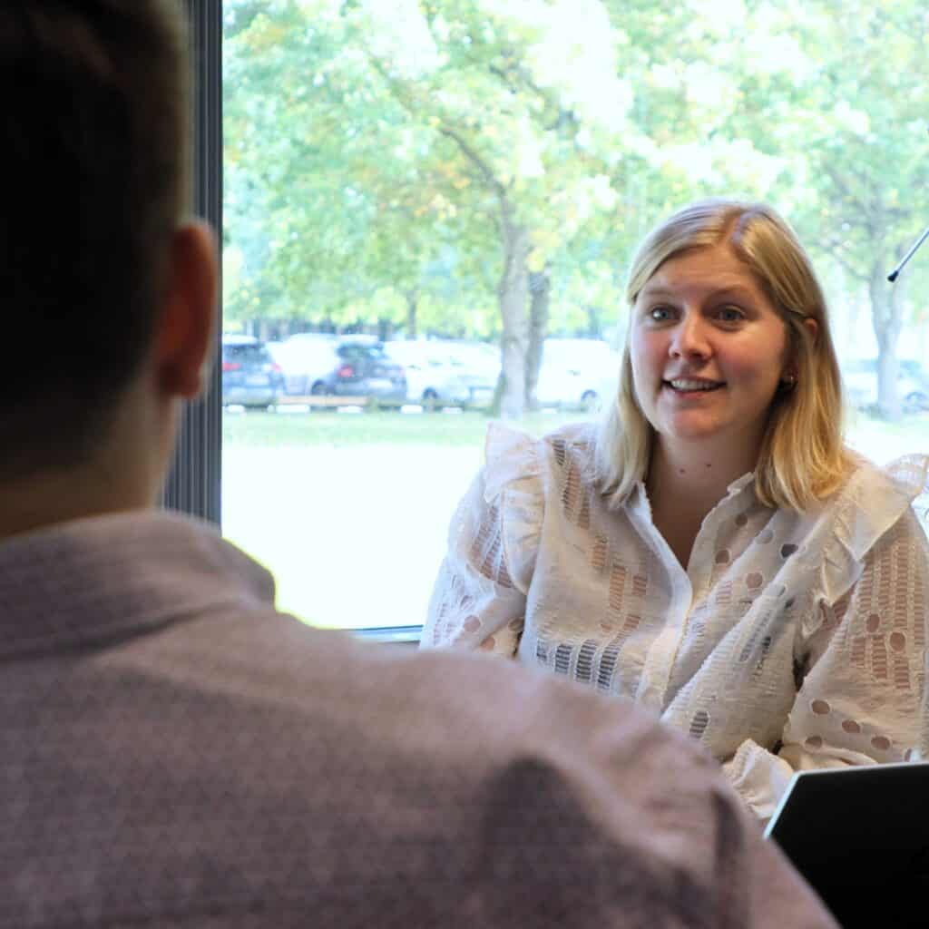 Kvinde holder medarbejderudviklingssamtale med kollega i kontormiljø.