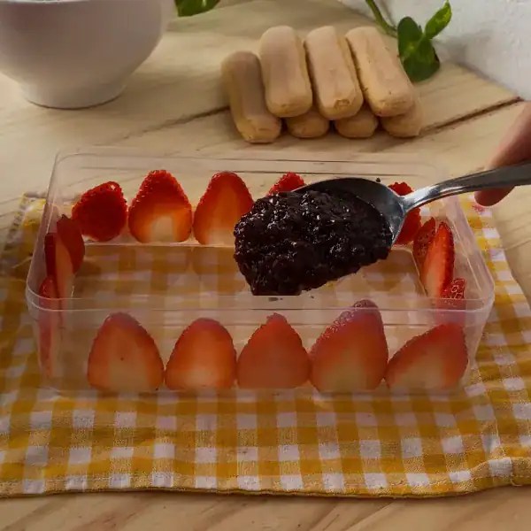 Sliced strawberries lining the sides of a container with a layer of strawberry jam