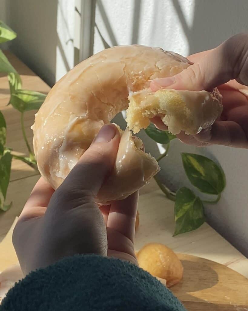 Fluffy glazed donut split in half, revealing its airy, soft interior with a shiny glaze on the outer surface