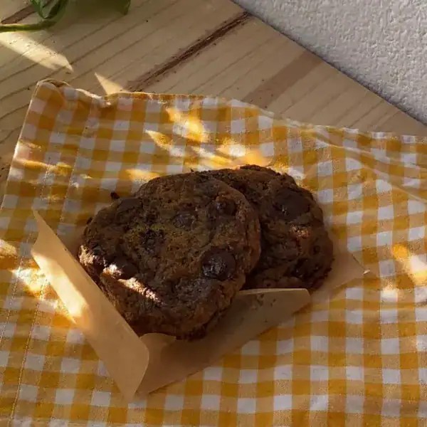 Two soft chocolate chip cookies placed on a small textile with orange and white squares