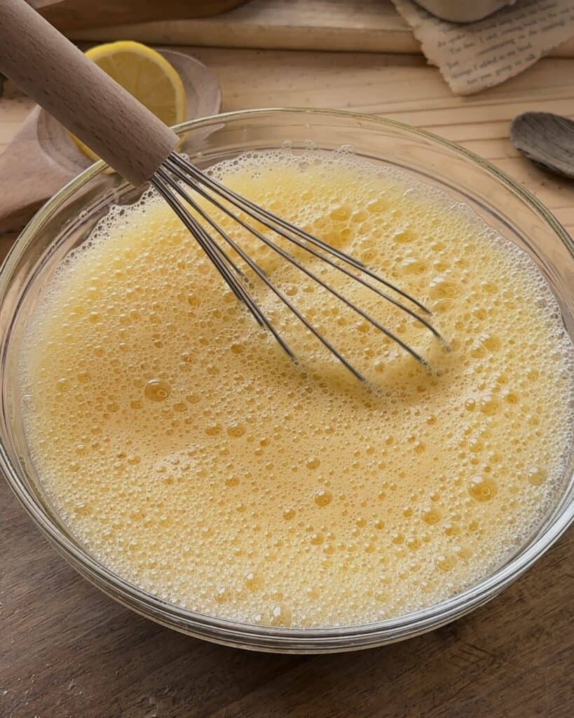 Whisking the eggs to create a light and airy texture, preparing the base for the cake layer in the homemade raspberry tiramisu