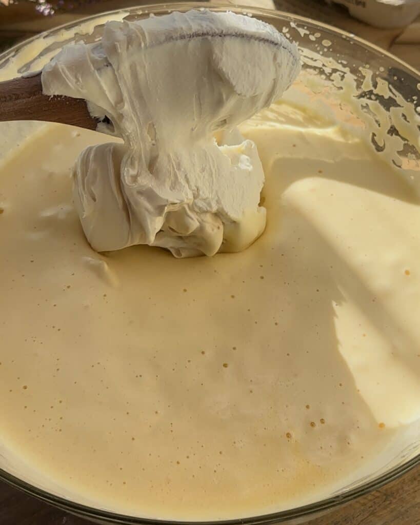 Mixing the whisked eggs with the smooth mascarpone cheese, creating a creamy, rich filling for the homemade raspberry tiramisu