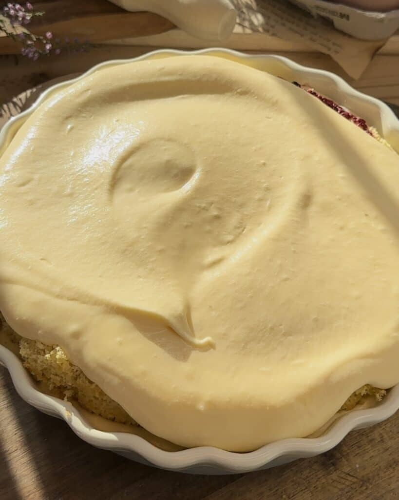Adding a creamy layer of mascarpone filling over the cake, creating a rich and smooth base for the homemade raspberry tiramisu