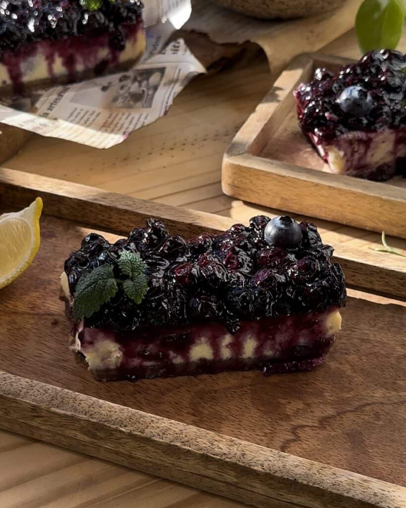 A delectable portion of irresistible blueberry cheesecake bars, featuring creamy cheesecake layers with a luscious blueberry swirl, ready to be savored