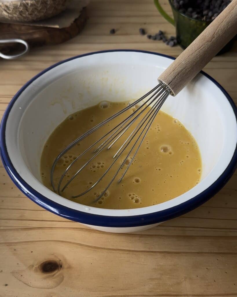 Mixing all the wet ingredients, including eggs, milk, oil, and vanilla extract, to create a smooth and creamy base for the chocolate cake batter