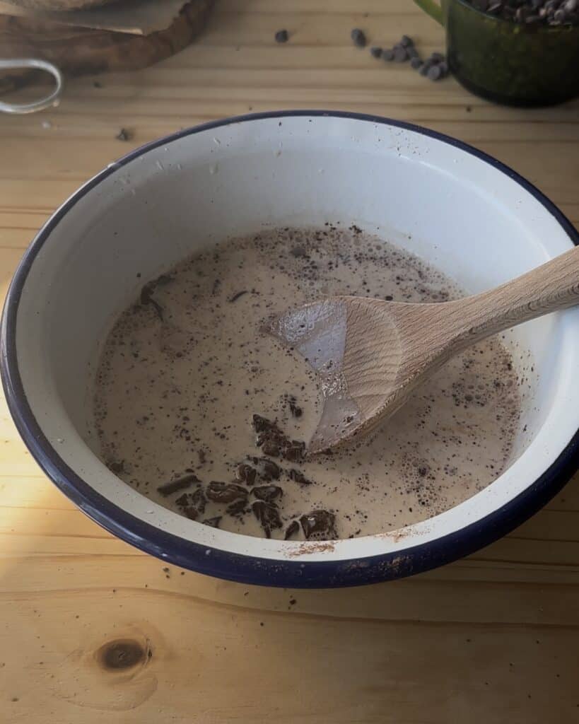 Mixing the melted chocolate and heavy cream together to create a smooth, velvety ganache for the chocolate cake