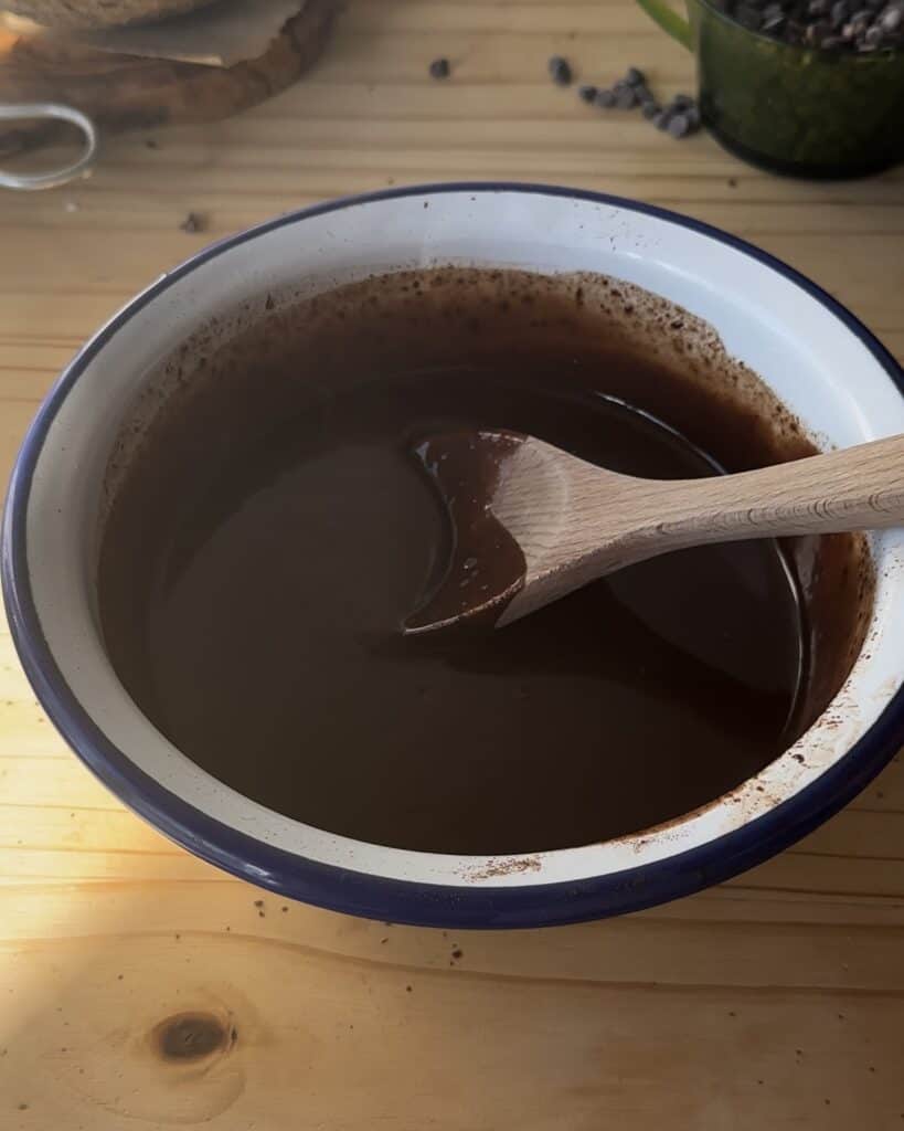 Mixing the melted chocolate and heavy cream together to create a smooth, velvety ganache for the chocolate cake