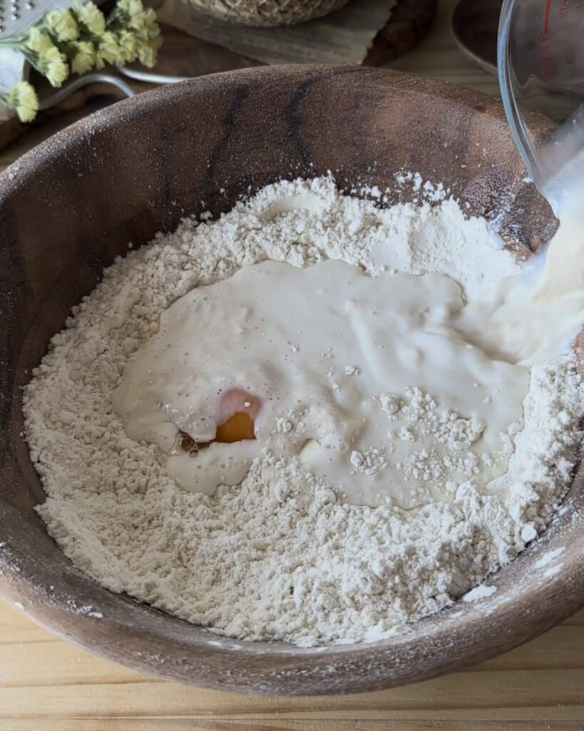 Mixing flour, sugar, butter, egg, salt, and the yeast mixture to create a smooth and rich dough for the bunny bread with chocolate