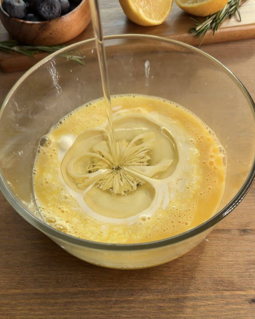 Combine eggs, sunflower oil, and milk to prepare the wet ingredients for bakery-style blueberry lemon muffins