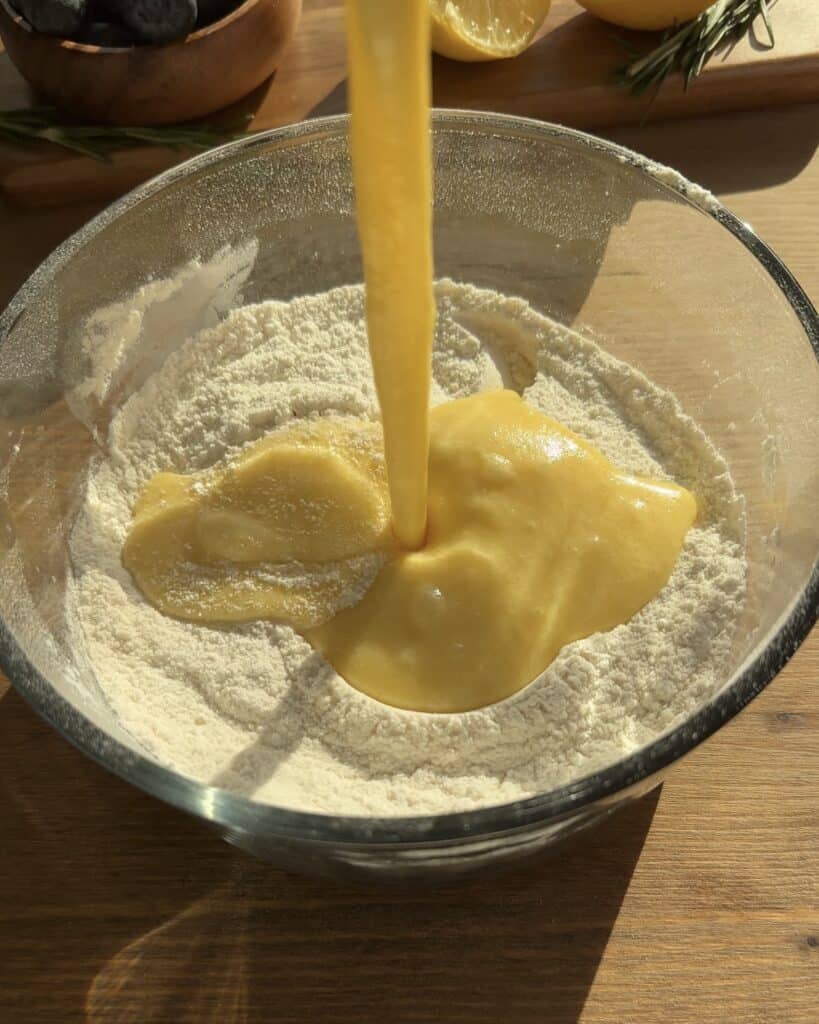 Add the wet ingredients to the dry ingredients and mix to create the batter for bakery-style blueberry lemon muffins