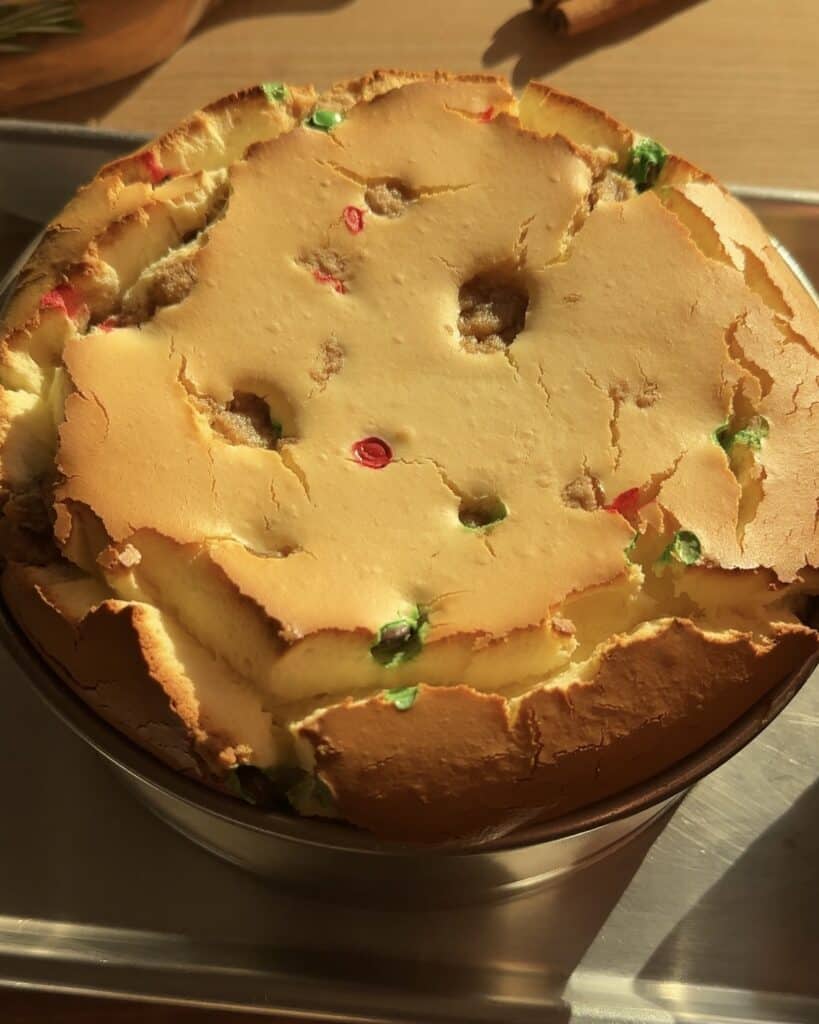 Freshly baked Christmas cookie dough cheesecake with a golden cookie dough crust, creamy cheesecake filling packed with red and green M&M’s and cookie dough chunks, just out of the oven.