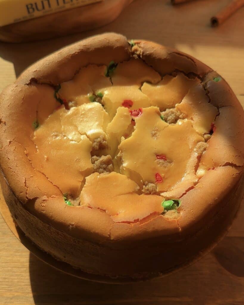 Freshly baked Christmas cookie dough cheesecake with a golden cookie dough crust, creamy cheesecake filling packed with red and green M&M’s and cookie dough chunks, just out of the oven.