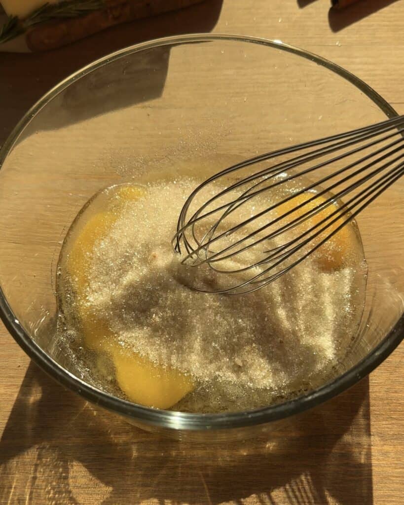 Beating eggs with sugar in a bowl to create a smooth and fluffy mixture for Christmas brownies batter. The creamy texture is perfect for the holiday season.