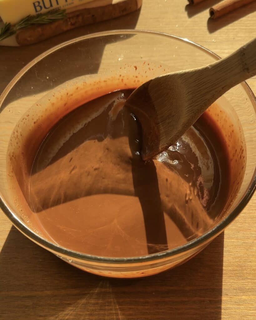 Mixing dark chocolate and brown butter in a heatproof bowl to create a rich, velvety Christmas brownies batter. Looks creamy, juicy, and perfect for the holiday season.
