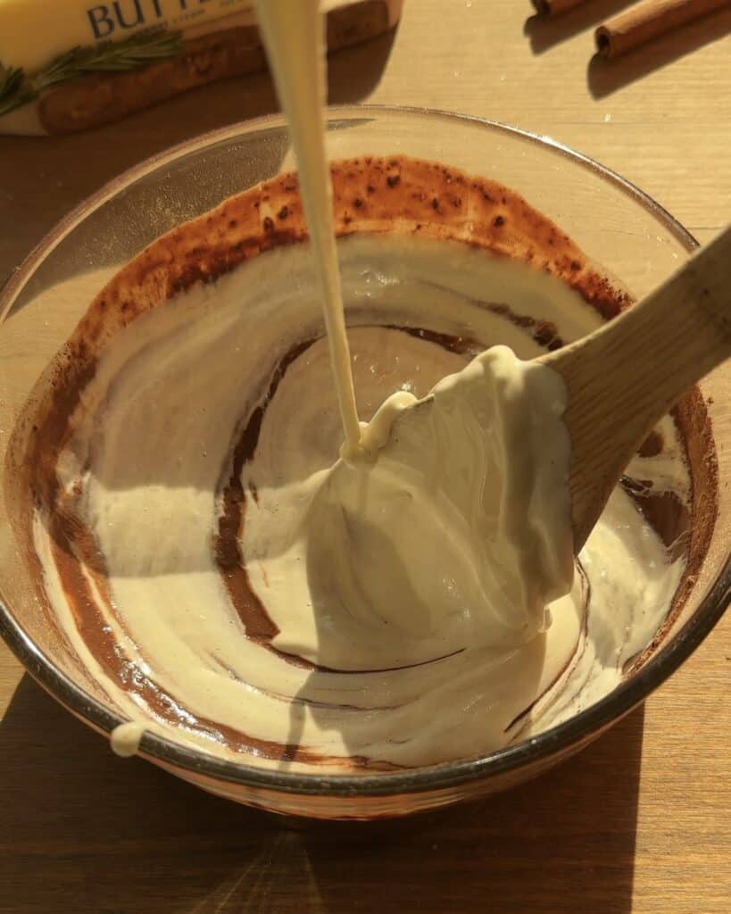 Mixing creamy and rich Christmas brownies batter in a bowl until smooth and homogeneous. A delicious chocolate base, perfect for holiday baking before adding toppings and baking.