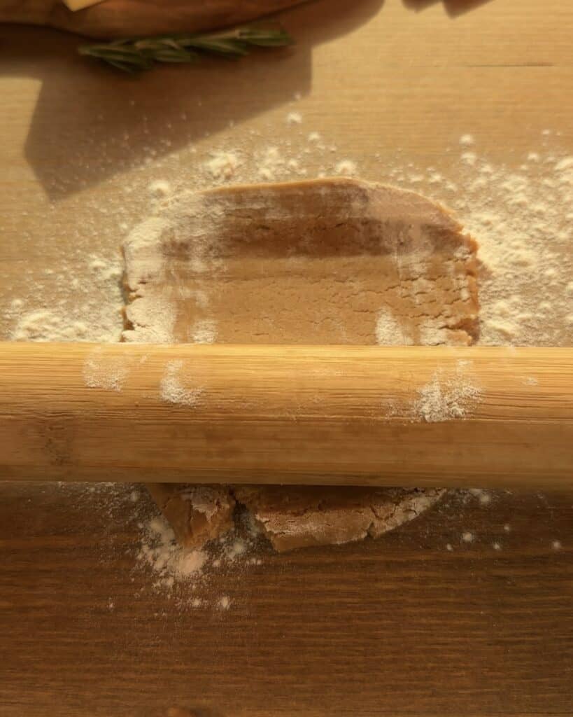 Rolling out the gingerbread cookie dough on a lightly floured surface to create the perfect spiced crust for a festive Gingerbread Apple Pie