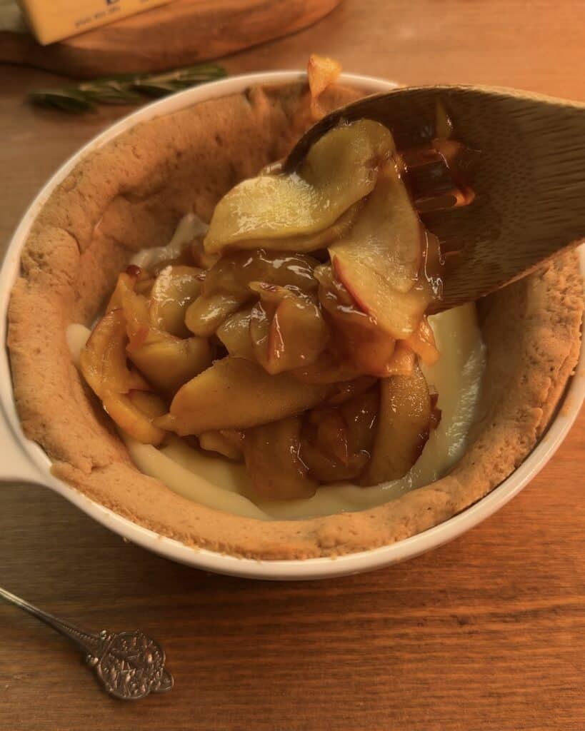 Adding the cinnamon-spiced apple filling on top of the creamy custard to make a delicious Gingerbread Apple Pie