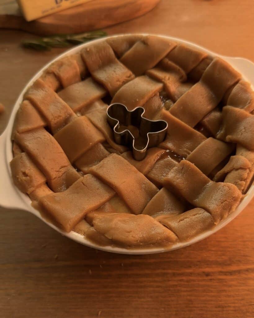 Placing a gingerbread mold on top of the Gingerbread Apple Pie for a festive and decorative finish