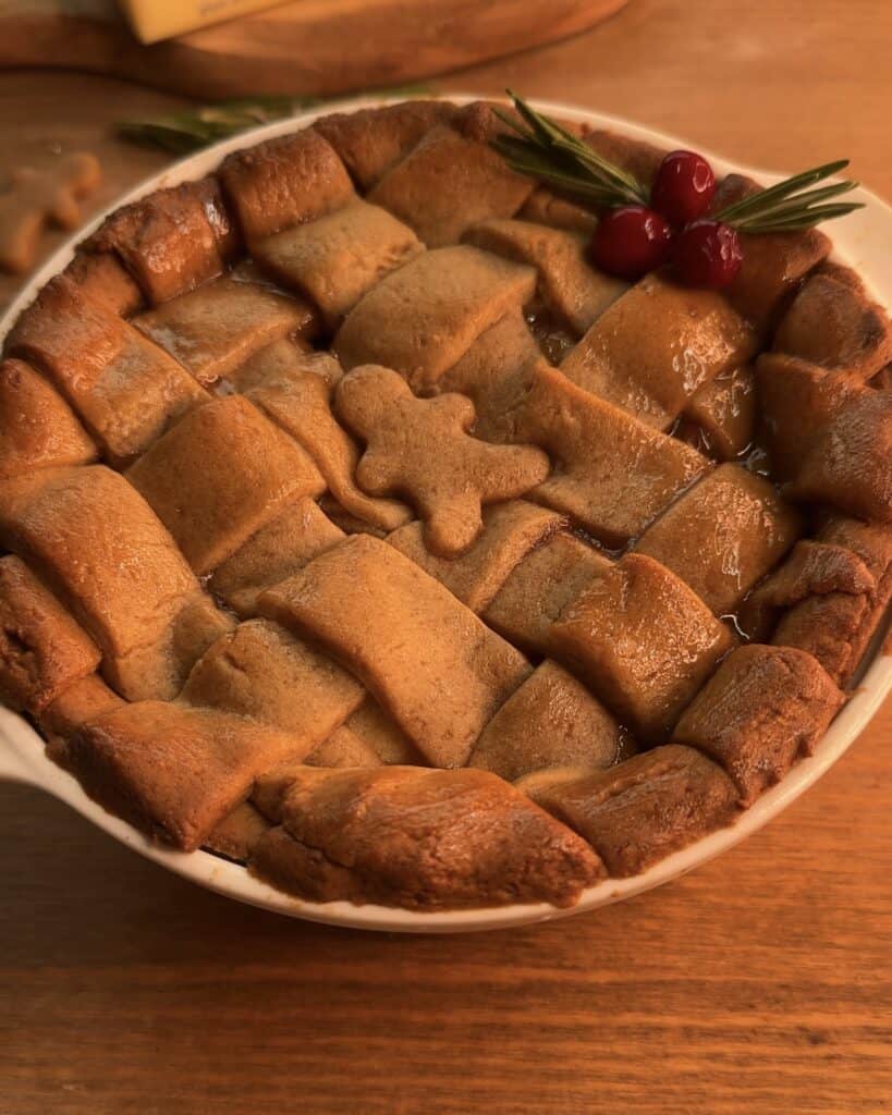 Delicious Gingerbread Apple Pie with Cranberries, featuring a festive gingerbread cookie dough crust and a cozy spiced apple pie filling with cranberries on top to decorate, perfect for the holidays