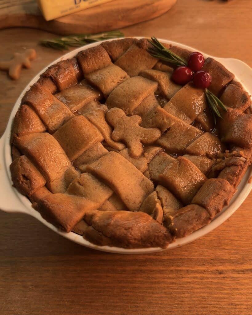 Delicious Gingerbread Apple Pie with Cranberries, featuring a festive gingerbread cookie dough crust and a cozy spiced apple pie filling with cranberries on top to decorate, perfect for the holidays
