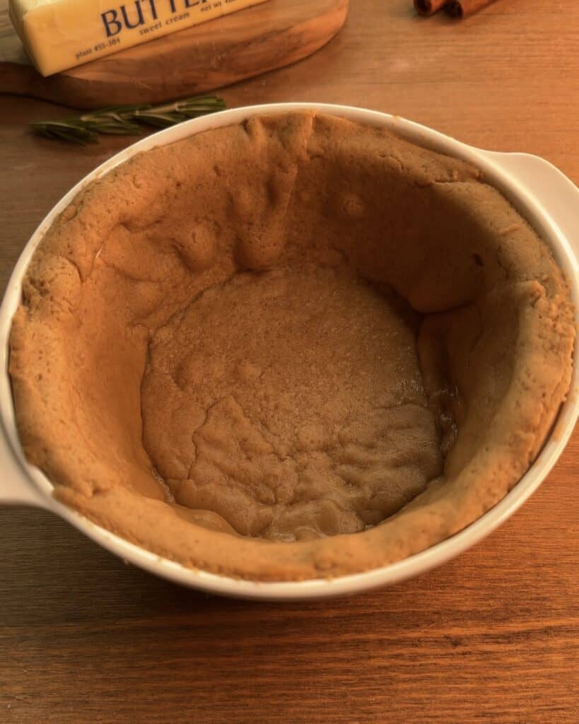 Gingerbread cookie dough in a greased pie mold, forming the spiced crust for a delicious Gingerbread Apple Pie with Cranberries on top to decorate