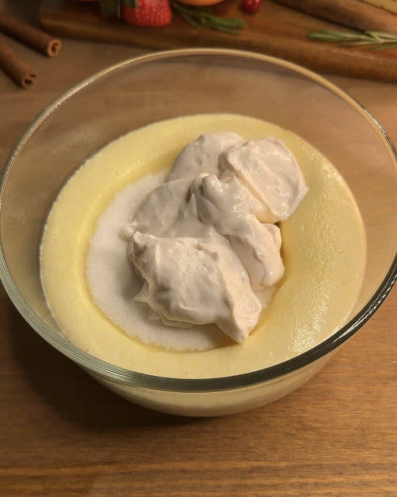 Adding Greek yogurt to the cheesecake mixture in a bowl, enhancing the creamy texture for Churro cheesecake bars
