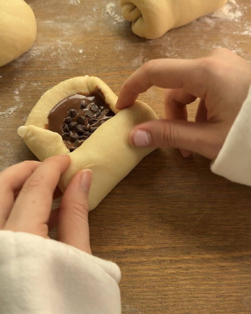 Shaping the Nutella-stuffed brioche by folding the dough around the filling and sealing it