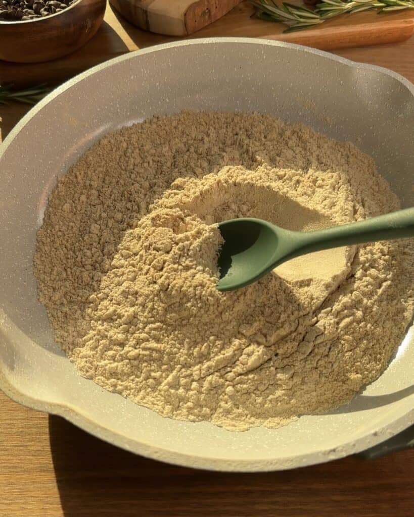 Toasting all-purpose flour and dry milk powder for Cookie Dough Muffins with chocolate, enhancing flavor and texture