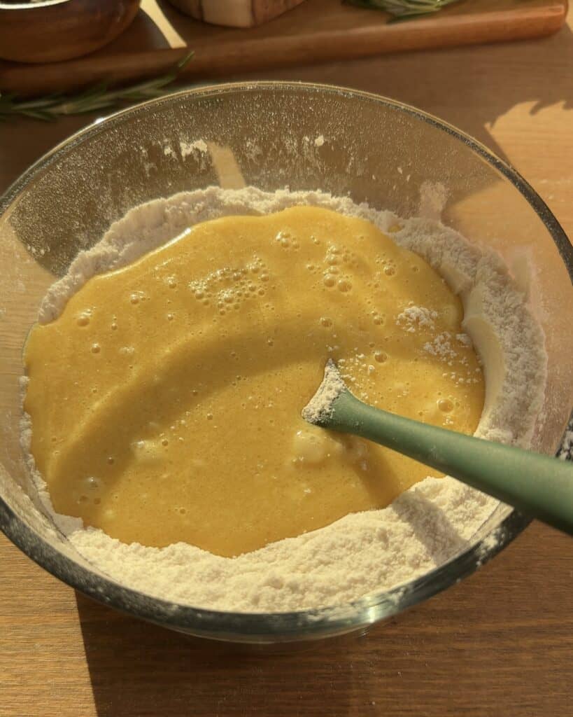 Mixing the wet ingredients into the dry ingredients to create the batter for Cookie Dough Muffins with chocolate