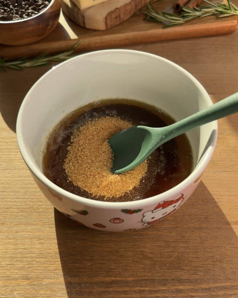 Mixing brown sugar with browned butter for Cookie Dough Muffins with chocolate, creating a rich and caramelized flavor