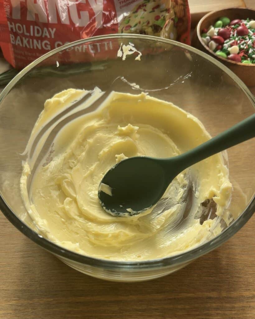 Soft butter being worked with a spoon until creamy for the Festive Holiday Cookies