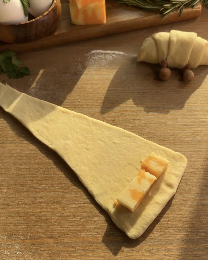 Filling the triangle-shaped Jellycat croissant dough with cheese before rolling and baking
