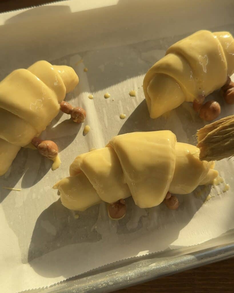 Brushing the Jellycat croissant with egg wash before baking to achieve a golden, glossy crust