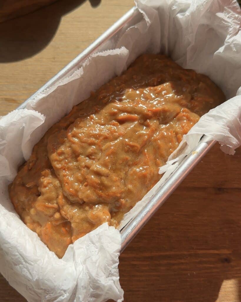 Carrot cake batter poured into a loaf pan, smooth and ready to bake into a moist and spiced holiday dessert.