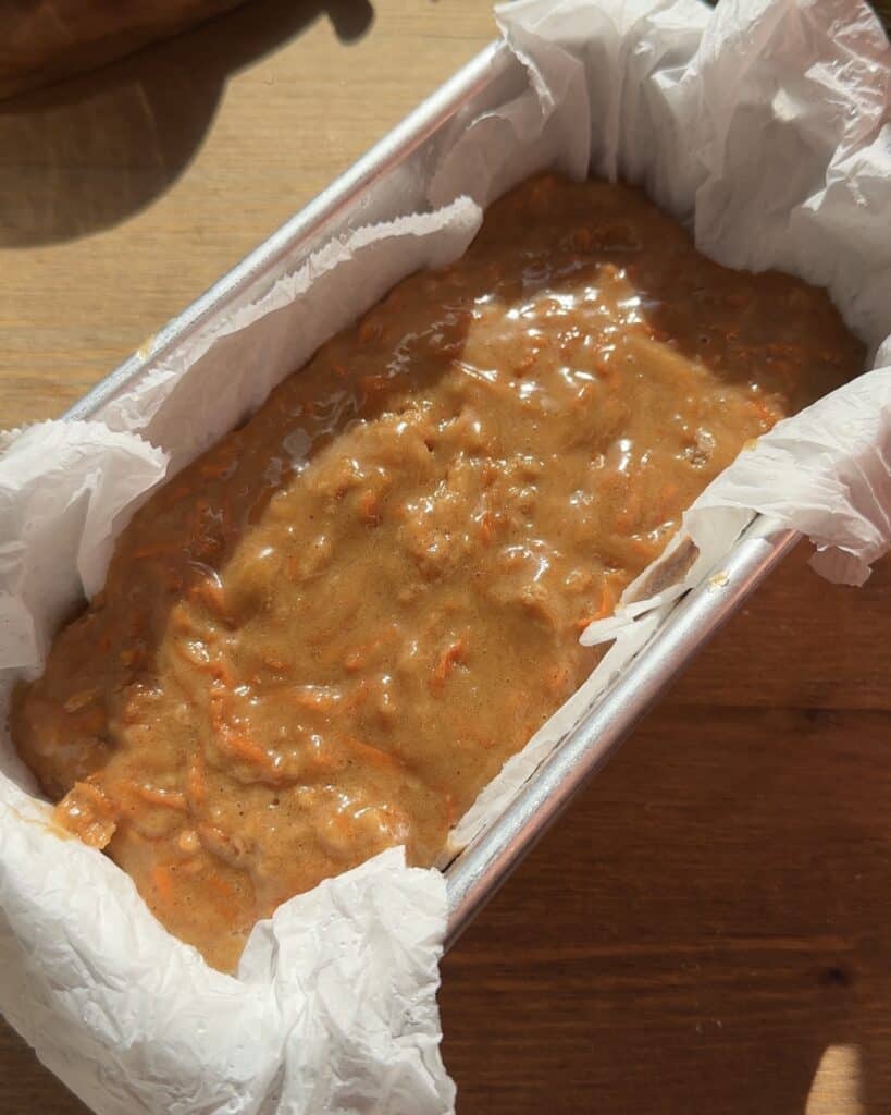 Carrot cake batter poured into a loaf pan, smooth and ready to bake into a moist and spiced holiday dessert.
