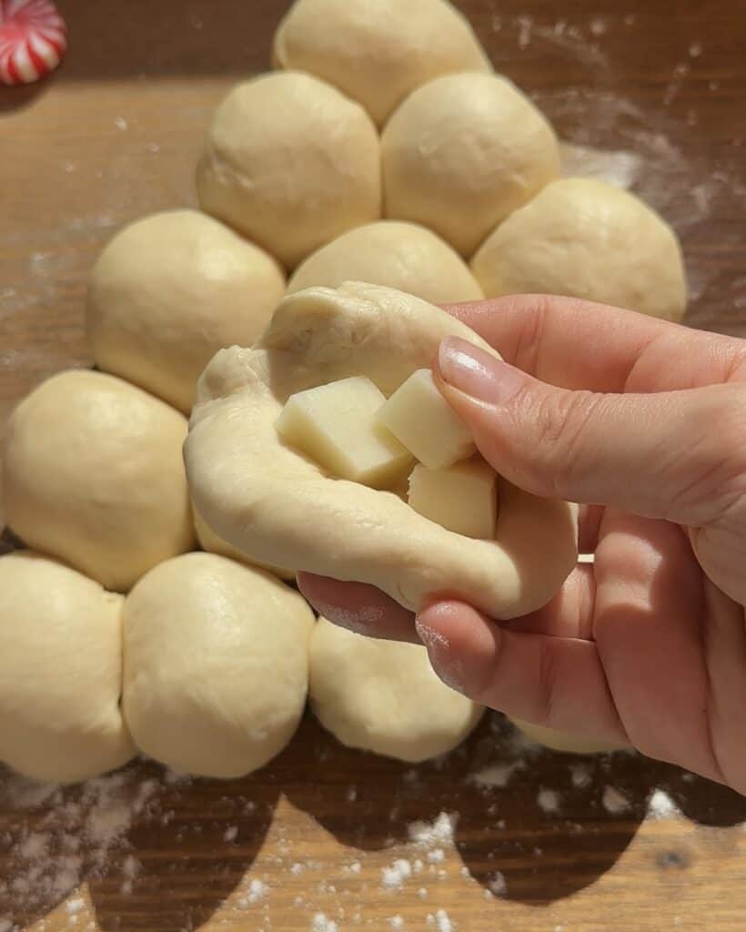 Portioned dough balls with cheese inside, ready to be closed and shaped into perfect little bites for the pull-apart Christmas tree garlic bread.