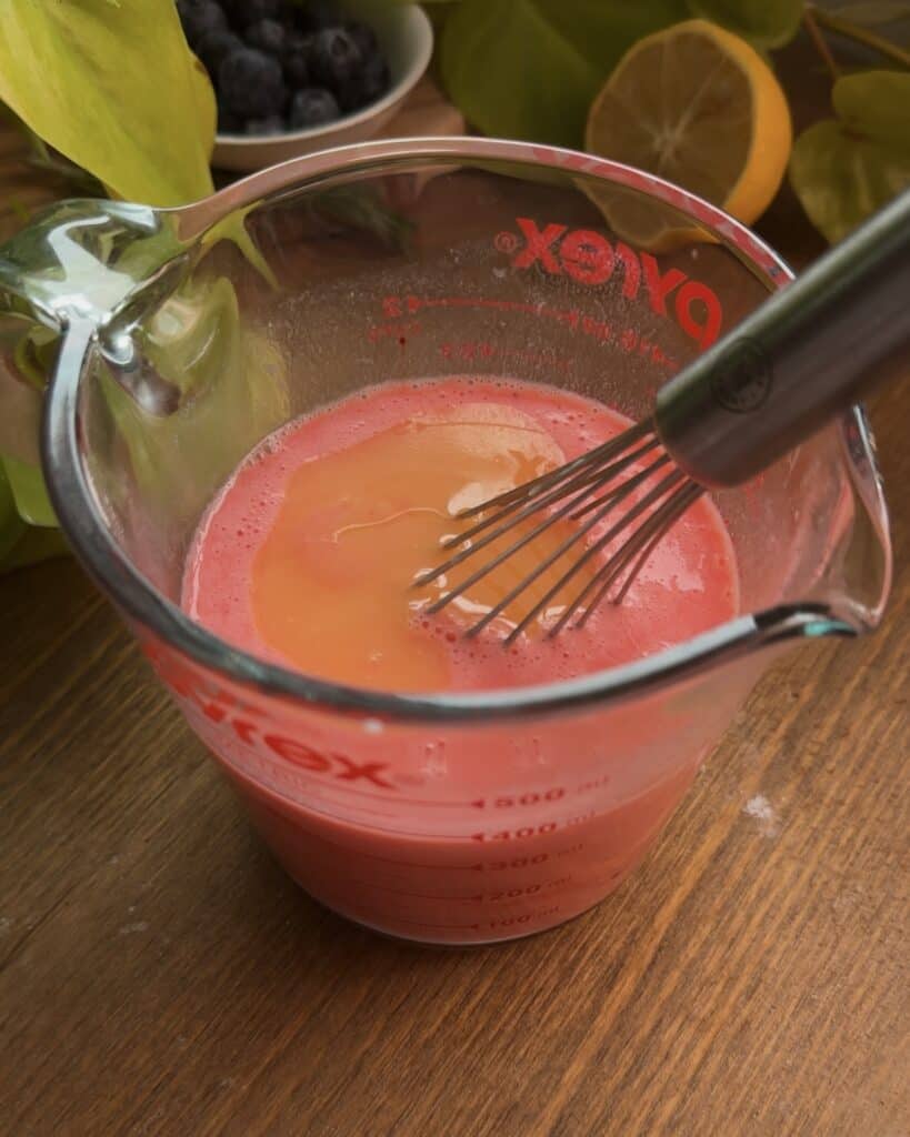 Mixed wet ingredients for red velvet Nutella pancakes in a bowl with melted butter on top