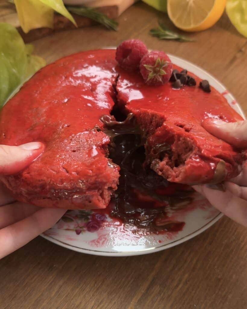 Red velvet Nutella stuffed pancake being cut open, revealing the gooey Nutella filling inside, creating a rich and indulgent dessert or breakfast treat