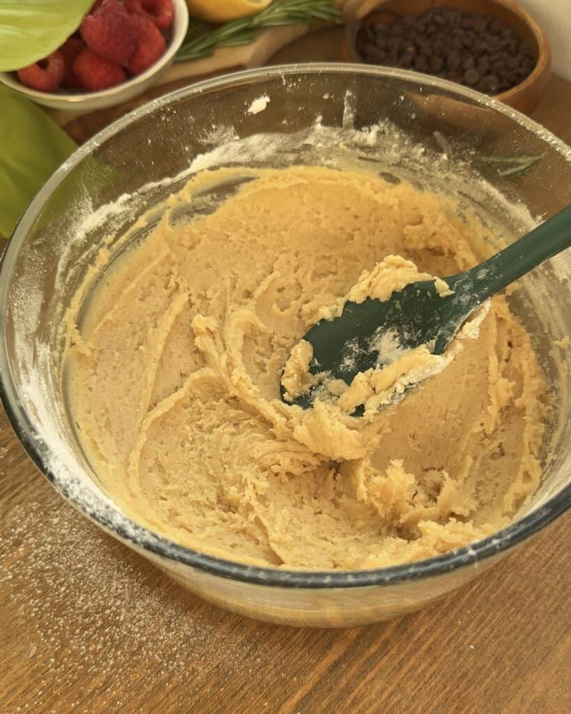 A mixing bowl containing a well blended mixture of melted butter, sugars, egg, vanilla and flour