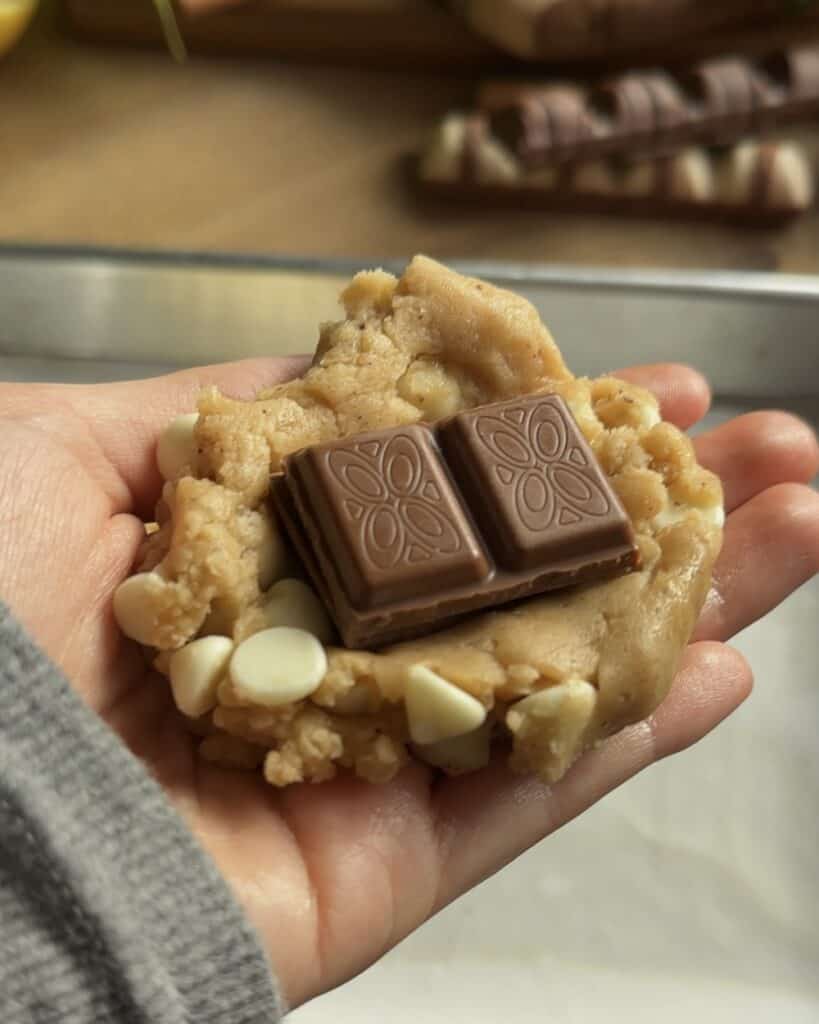 Closeup of Kinder Bueno cookie dough with chocolate chips placed on top, about to be covered with more dough before baking into soft, gooey cookies.