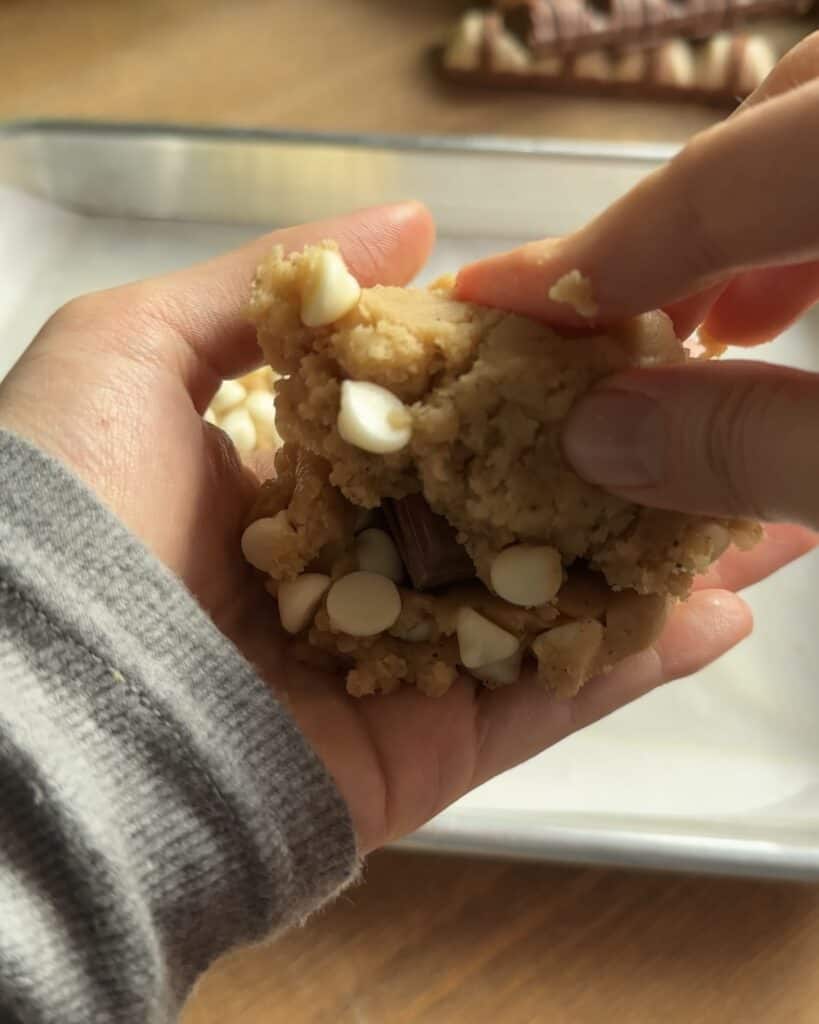 Closeup of Kinder Bueno cookie dough with chocolate chips placed on top, about to be covered with more dough before baking into soft, gooey cookies.
