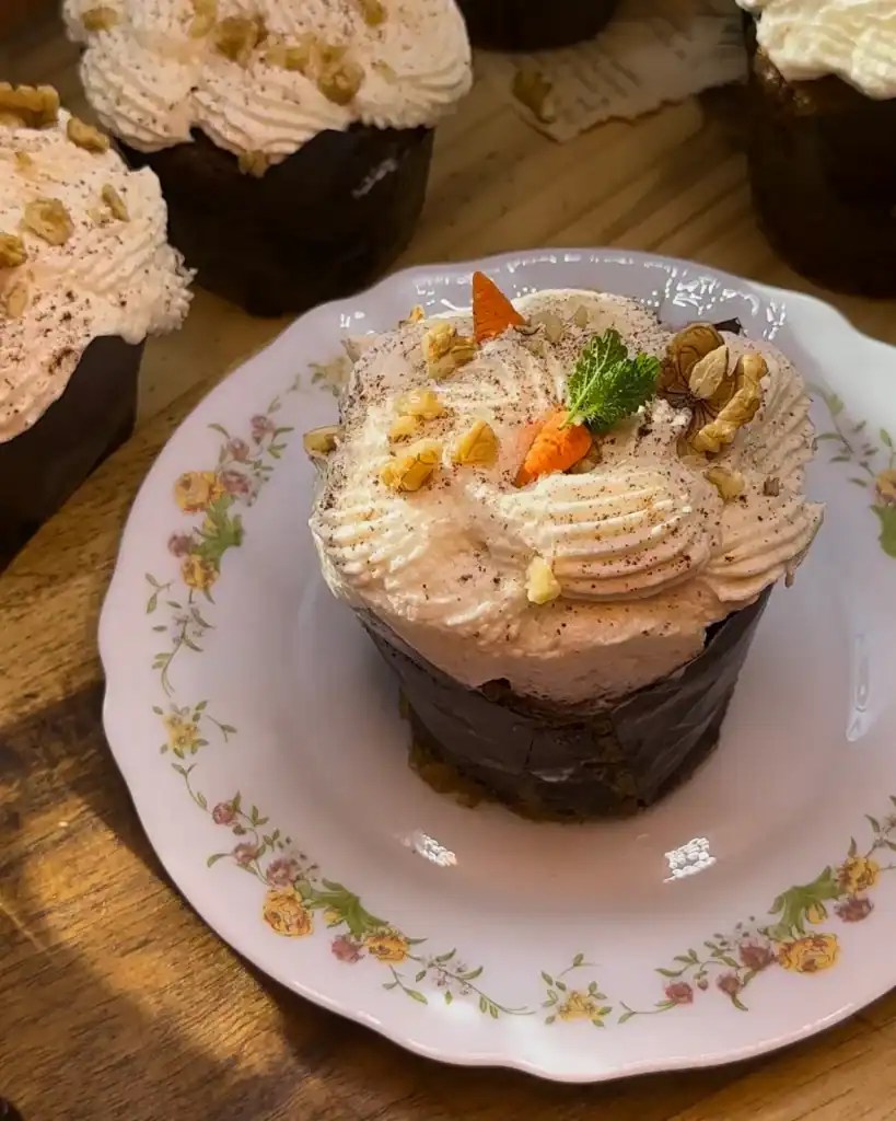 Carrot cake muffin topped with crunchy walnuts and a decorative chocolate carrot