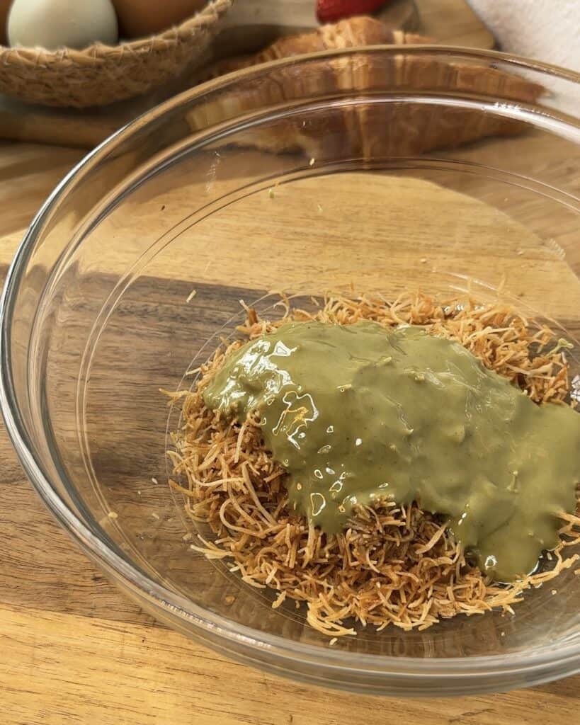 "A bowl filled with toasted kataifi and pistachio spread, ready to be mixed together for a delicious filling."