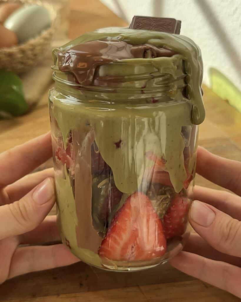 "Close-up of a jar filled with Dubai chocolate strawberries, showcasing the layers of kataifi pastry, pistachio cream, and melted chocolate. The crispy, toasted kataifi adds a delightful crunch, contrasting beautifully with the soft strawberries and creamy pistachio, creating a luxurious and flavorful dessert."